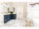 Bathroom with dual sinks, blue cabinets, marble floor and adjacent soaking tub at 825 Glengate Pl, Atlanta, GA 30328
