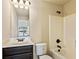 Bright bathroom with a white tub and shower combination and dark cabinetry with a window view at 1301 Odell Ct, Hoschton, GA 30548