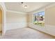 Empty dining room with decorative wall trim, carpeted flooring, and a view of the front yard at 1301 Odell Ct, Hoschton, GA 30548