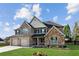 Beautiful two-story home with stone accents, three-car garage, a well-kept lawn, and colorful flower beds at 1301 Odell Ct, Hoschton, GA 30548