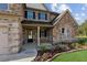 Charming front porch with stone columns, lush landscaping, and a welcoming entrance to this lovely home at 1301 Odell Ct, Hoschton, GA 30548
