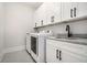 Bright laundry room featuring white cabinetry, granite countertop and black hardware at 396 Academy St, Alpharetta, GA 30009