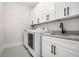 This laundry room features a washer and dryer, white cabinetry, granite countertops, and a sink at 396 Academy St, Alpharetta, GA 30009