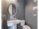 Stylish half bathroom with a pedestal sink, oval mirror, and gray walls at 6601 Cadence Blvd, Atlanta, GA 30328