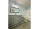Bright bathroom features gray vanity, large mirror, and tub with shower at 5075 Forest Downs Ln, Atlanta, GA 30349
