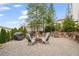 Private backyard features a fire pit area with seating, stone retaining wall, and lush landscaping at 6845 Wesley Hughes Rd, Cumming, GA 30040
