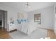 Bright bedroom features hardwood floors, a large window, and a comfortable bed with accent pillows at 6845 Wesley Hughes Rd, Cumming, GA 30040