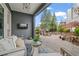 Covered patio area features a stone paver floor, outdoor seating, a built-in TV, and a view of the backyard at 6845 Wesley Hughes Rd, Cumming, GA 30040