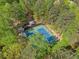 An aerial shot showcases blue tennis courts surrounded by dense green trees in a private community setting at 10070 Timberstone Rd, Johns Creek, GA 30022