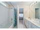 Bathroom with white tiles and cabinetry, a tub-shower combo, and bedroom view at 1192 Lake Washington Dr, Lawrenceville, GA 30043