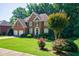 Lovely brick home featuring lush green lawn, mature trees, and colorful rose bushes at 1192 Lake Washington Dr, Lawrenceville, GA 30043