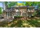 The backyard features green grass, mature trees and the back of the home with a chimney at 7045 Threadstone Overlook, Johns Creek, GA 30097