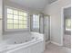 Bathroom featuring a soaking tub, glass-enclosed shower and natural light at 7045 Threadstone Overlook, Johns Creek, GA 30097
