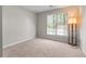 This bedroom features neutral paint, carpet and a window letting in natural light at 7045 Threadstone Overlook, Johns Creek, GA 30097