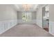 Bright dining room featuring wainscoting, neutral walls, carpet, and a stylish chandelier at 7045 Threadstone Overlook, Johns Creek, GA 30097