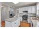 Well-lit kitchen with white cabinets, granite countertops, stainless steel appliances, and wood floors at 7045 Threadstone Overlook, Johns Creek, GA 30097