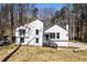 A shot of the white siding, modern house exterior with black trim, set amidst a natural wooded backdrop at 5017 Tanaga Ct, Stone Mountain, GA 30087