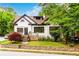 Charming two-story home with white painted brick, dark trim, landscaped yard, and stone accent wall at 1448 N Highland Ne Ave, Atlanta, GA 30306