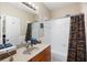 A bathroom featuring a wood vanity and shower-tub combo with white tile surround at 1020 Constitution Way, Cumming, GA 30040