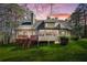 Back of the house featuring a deck, sunroom, green lawn, and mature trees at sunset at 2051 E Piedmont Rd, Marietta, GA 30062