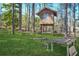 A backyard playhouse and benches surrounded by mature trees and lush greenery at 2051 E Piedmont Rd, Marietta, GA 30062