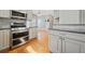 Bright kitchen features stainless steel appliances, light grey cabinetry, stone backsplash and hardwood floors at 2051 E Piedmont Rd, Marietta, GA 30062