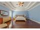 Cozy main bedroom featuring tray ceiling, wood floors, and neutral walls with large windows at 1913 Shenley Park Ln, Duluth, GA 30097