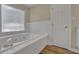 This bathroom features a soaking tub with jets, wood flooring, and a frosted window at 2000 Mcconnell Rd, Grayson, GA 30017