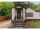 Charming exterior view of the front of the house with beautiful landscaping, stairs leading to the front door and mature trees at 1291 Oakland Sw Ter, Atlanta, GA 30310