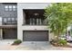 Attached garage with an overhead door, balcony above, and landscaped front yard at 6596 Aria Village Dr # 642, Atlanta, GA 30328