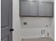 Well-lit laundry room with gray cabinets for ample storage and tile floors at 6739 Encore Blvd, Atlanta, GA 30328