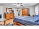 A cozy bedroom featuring wood floors, ceiling fan and a large wooden dresser with a large mirror and a striking blue comforter at 9224 Snipe Ln, Jonesboro, GA 30236