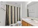 Bathroom featuring a striped shower curtain, white toilet, and a white sink with wood cabinet at 6450 Wellington Chase Ct, Lithonia, GA 30058