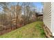 View of the backyard and deck with a grassy slope, trees, and a view of a wooded area behind the house at 174 Whetstone Way, Villa Rica, GA 30180