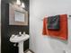 Modern powder room featuring a pedestal sink, ornate mirror, and stylish black accent wall at 407 The Crossings Ln, Woodstock, GA 30189