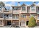 Attractive townhouse exterior with stone accents, covered parking, and balcony on a sunny day at 407 The Crossings Ln, Woodstock, GA 30189