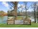 A wooden back deck overlooks a pristine lake surrounded by mature trees and docks at 6313 Shoreland Cir, Buford, GA 30518