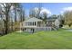 Backyard view of a beautiful home with a large deck, lush green lawn, and mature trees at 6313 Shoreland Cir, Buford, GA 30518