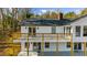 Rear view of a home featuring a large deck, white siding, and landscaped backyard with mature trees at 6313 Shoreland Cir, Buford, GA 30518