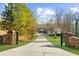 Stone gated entrance opens to a long driveway with manicured lawns, trees, and leads to a beautiful home at 6313 Shoreland Cir, Buford, GA 30518