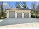 Exterior shot of a detached three-car garage with white siding and gray doors at 6313 Shoreland Cir, Buford, GA 30518