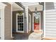 Cozy front porch with red door, brick flooring, and hanging flower basket creates a welcoming entrance at 356 Ivy Glen Cir, Avondale Estates, GA 30002