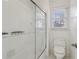 Shower and toilet in a well-lit bathroom with white tile and a glass shower door at 6230 Hampton Highlands Dr, Cumming, GA 30041