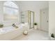 A bright bathroom features an arched window above the tub and a separate glass-enclosed shower at 6230 Hampton Highlands Dr, Cumming, GA 30041