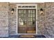Elegant double front doors with glass panes, flanked by sconces and set in a stone facade at 6230 Hampton Highlands Dr, Cumming, GA 30041