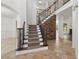 Elegant staircase with wooden railings, carpeted steps, and a stone accent wall at 6230 Hampton Highlands Dr, Cumming, GA 30041