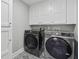 Convenient laundry room with front load washer and dryer, white cabinets and striking patterned floor tiles at 708 Larkspur Nw Blvd, Acworth, GA 30102