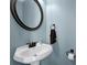 Stylish powder room featuring a pedestal sink, round mirror, and modern fixtures, adding a touch of elegance at 1952 Appaloosa Mill Cir, Buford, GA 30519