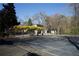 The tennis court is near the house and is framed by trees with yellow flowers at 2211 Surrey Se Ct, Marietta, GA 30067
