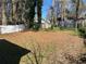 Expansive backyard with a mix of grass and pine straw beneath mature trees and a white fence at 2938 Palm Dr, Atlanta, GA 30344